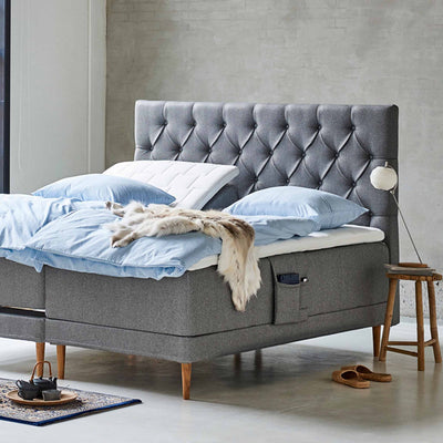 Chest sengegavl i bredde 210 cm betrukket med stof i stilren grå farve.